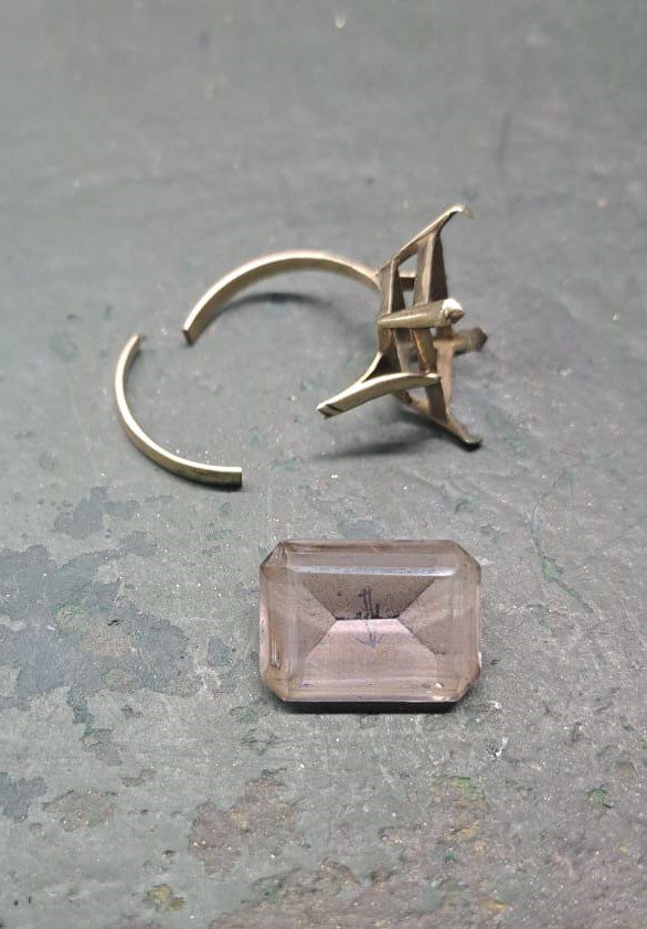 Broken ring with a worn-out, faded gemstone and visible metal damage before restoration