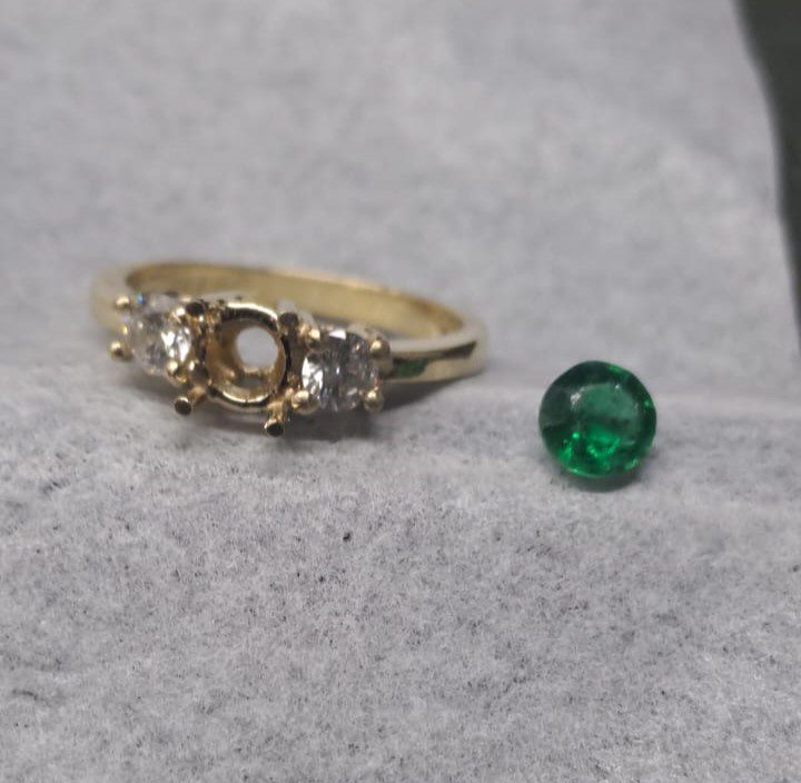 Gold ring with an empty center setting, previously holding a green gemstone